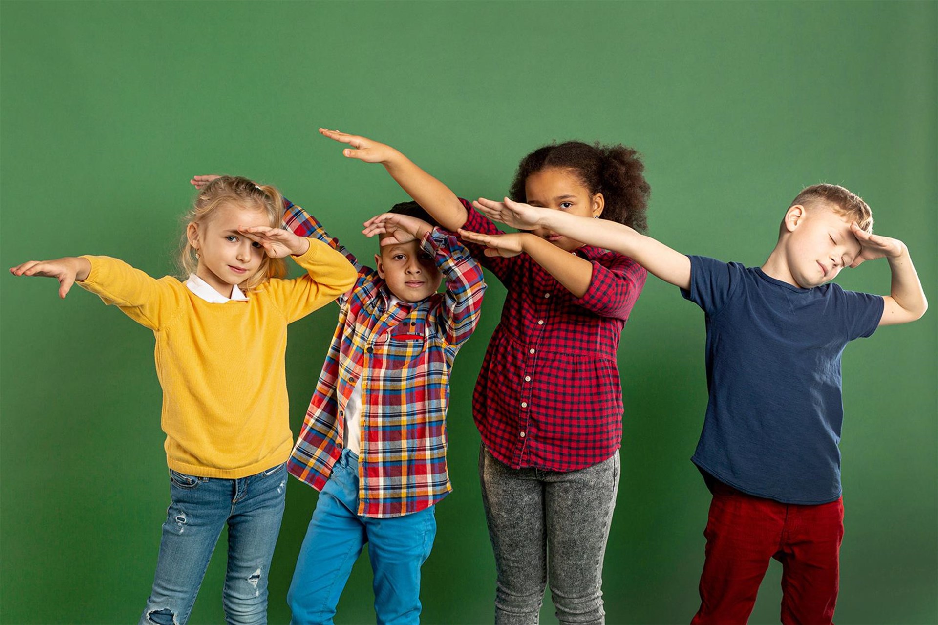 4 Kinder in bunter Kleidung stehen vor einem dunkelgrünen Hintergrund. Sie halten die Arme schräg nach rechts