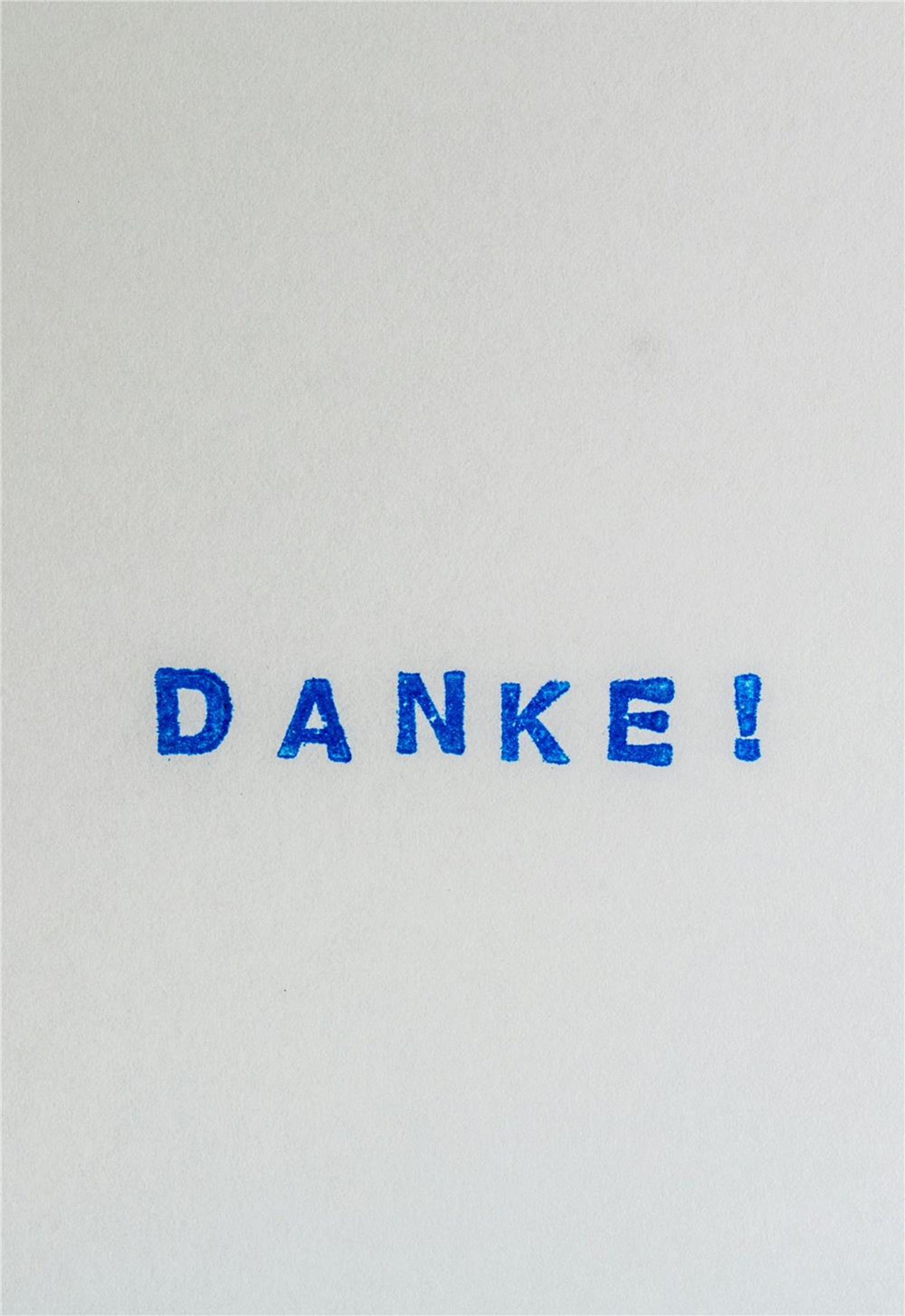 Das Wort "Danke" in blauer Schrift auf einer weißen Wand