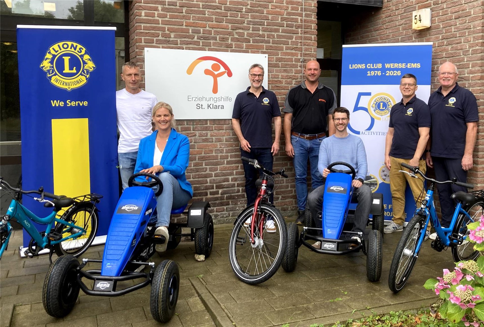 Verena Westermann und Manuel Brohl sitzen auf Kettcars. 
Die Vertreter von Lions Club, Agravis und dem Beckumer Fahrradlager stehen dahinter. 