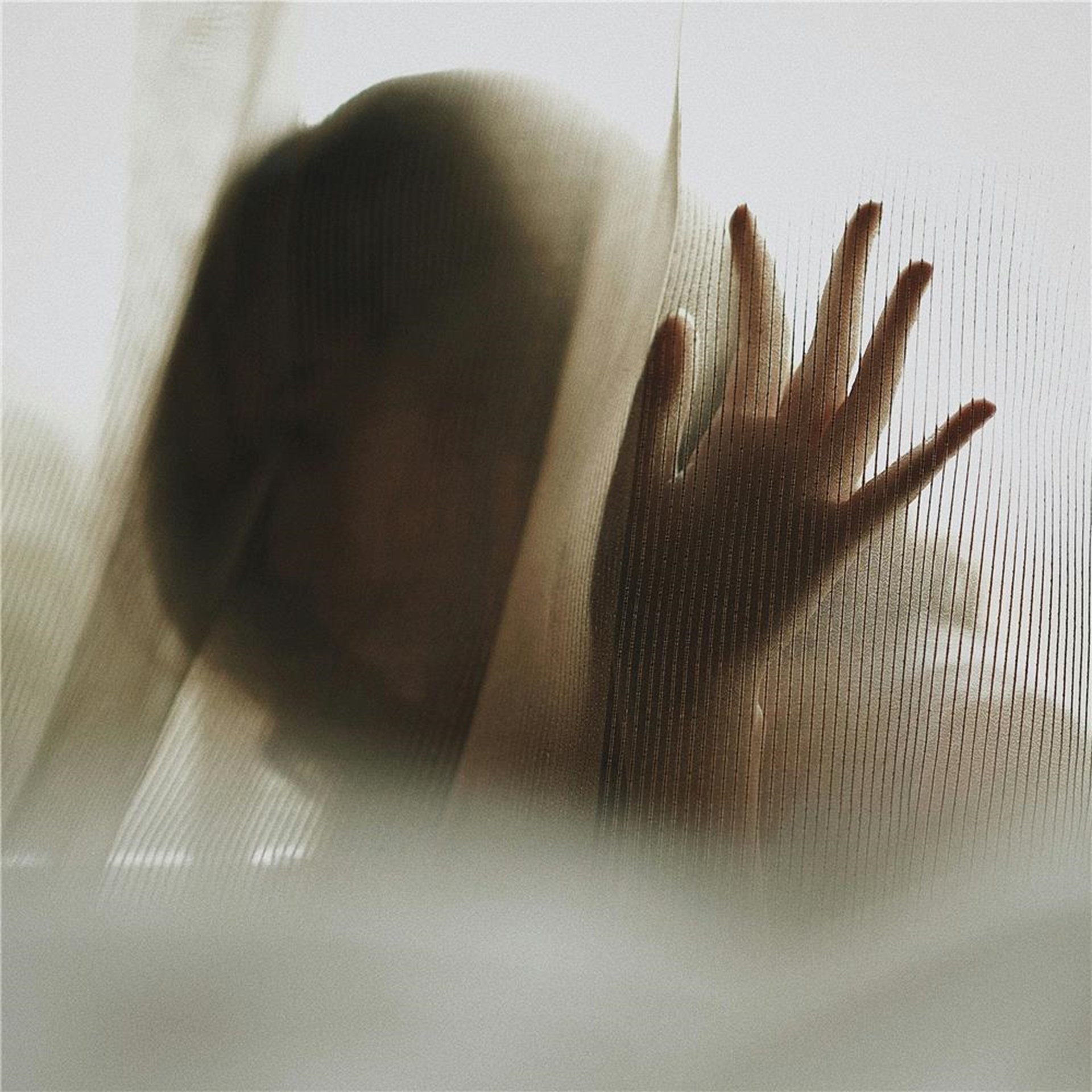 Das Foto zeigt eine Mädchensilhoutte hinter einem weißen Vorhang. Es sind nur der Umriss vom Kopf und von der Hand zu sehen