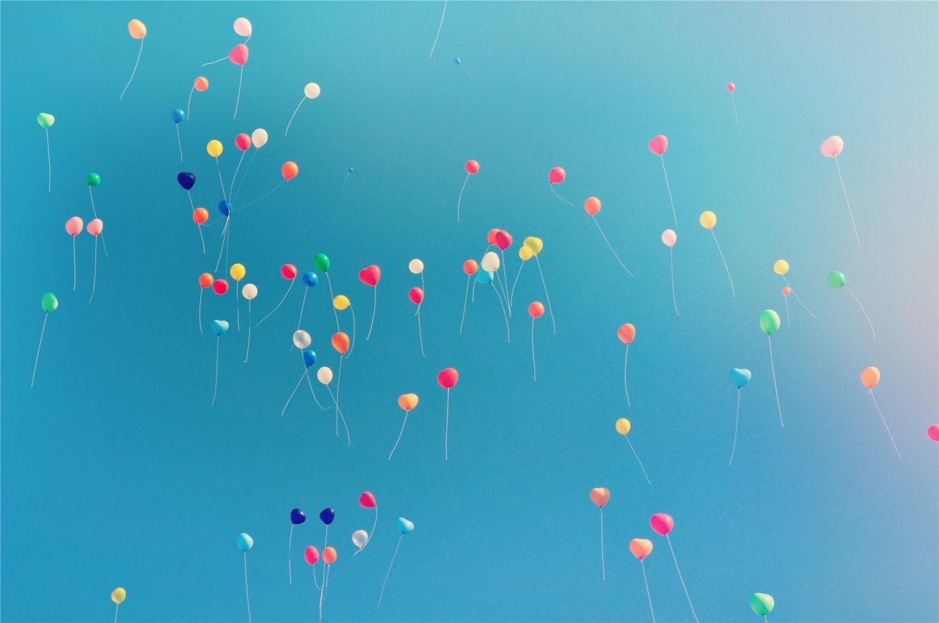 Das Foto zeigt viele bunte Luftballons vor blauem Himmel