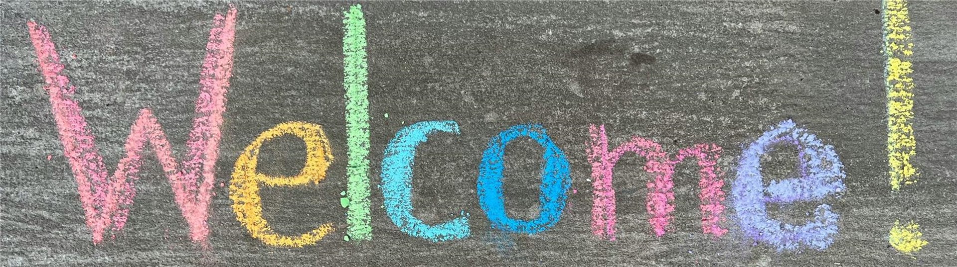 Mit bunter Kreide auf Stein ist das Wort "Welcome" gemalt. 