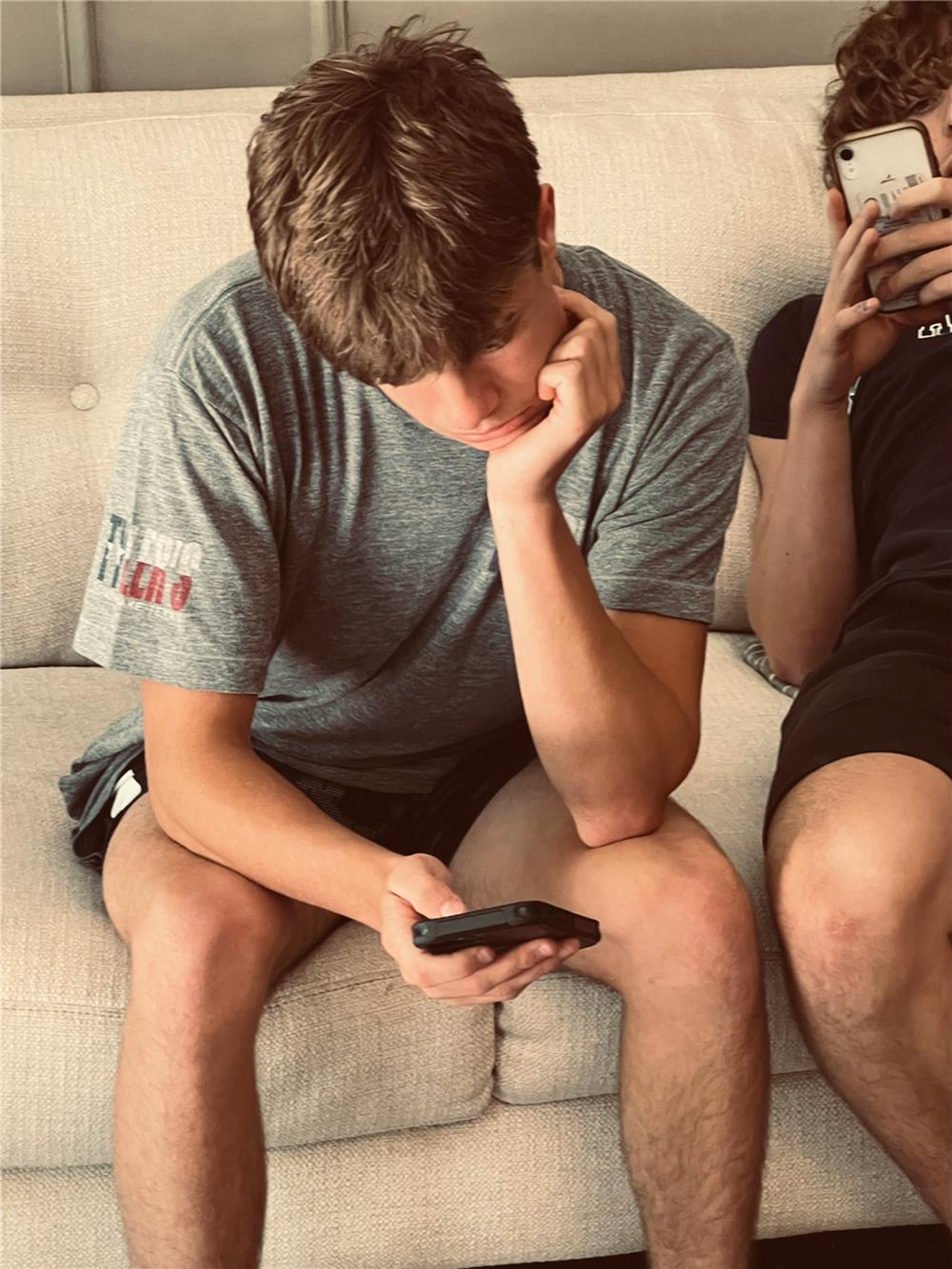 Zwei Jungs sitzen auf dem Sofa und schauen auf ihre Smarthphones. 